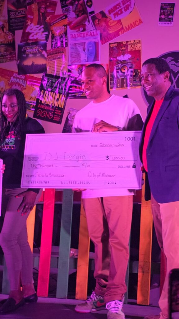 DJ Fergie receives prize with Alexandra P. Davis and former Broward County Mayor Dale Holness.